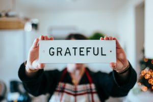 Person holding sign that reads 'GRATEFUL'